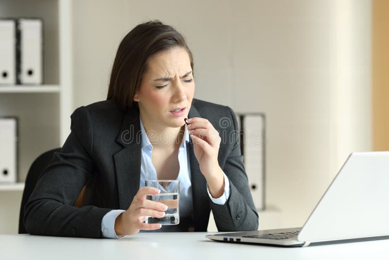 Ill businesswoman complaining and taking pill at office