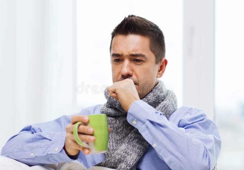 Ill man with flu drinking tea and coughing at home stock photography Ill man with flu drinking tea and coughing at home stock photography