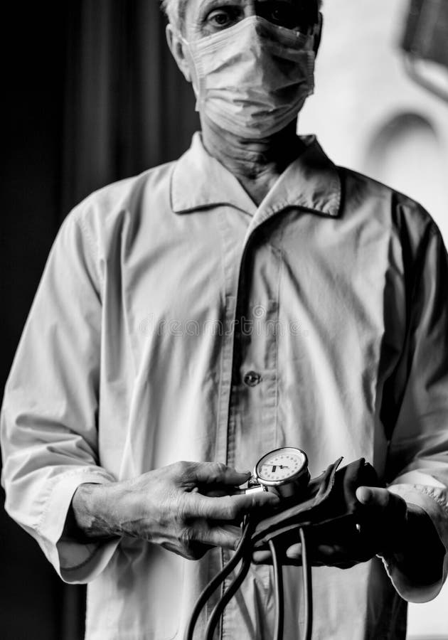 Ill with Mask with Blood Pressure Measuring Device in the Hands Stock