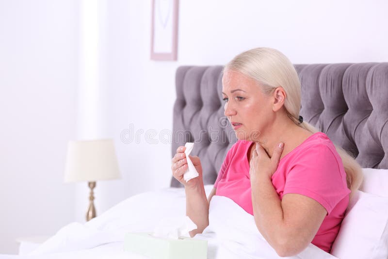 Ill mature woman suffering from cough in bed. royalty free stock image Ill mature woman suffering from cough in bed. royalty free stock image
