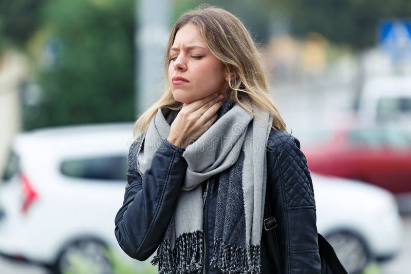 Illness young woman with terrible throat pain walking to the street. royalty free stock images Illness young woman with terrible throat pain walking to the street. royalty free stock images