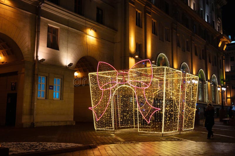 Illuminated gift box display with twinkling lights in urban nighttime setting royalty free stock photo