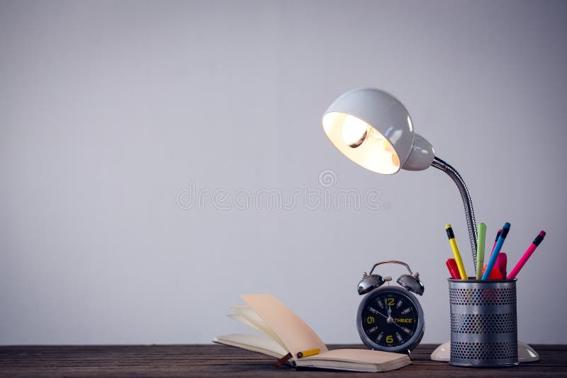 Illuminated lamp with desk organizer by book and alarm clock