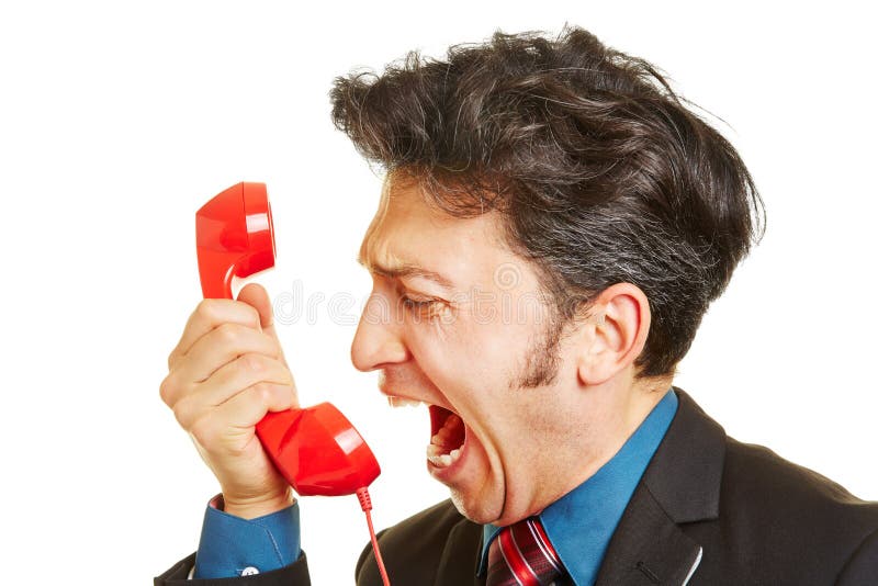 Angry business man screaming loudly into a red phone receiver. Angry business man screaming loudly into a red phone receiver