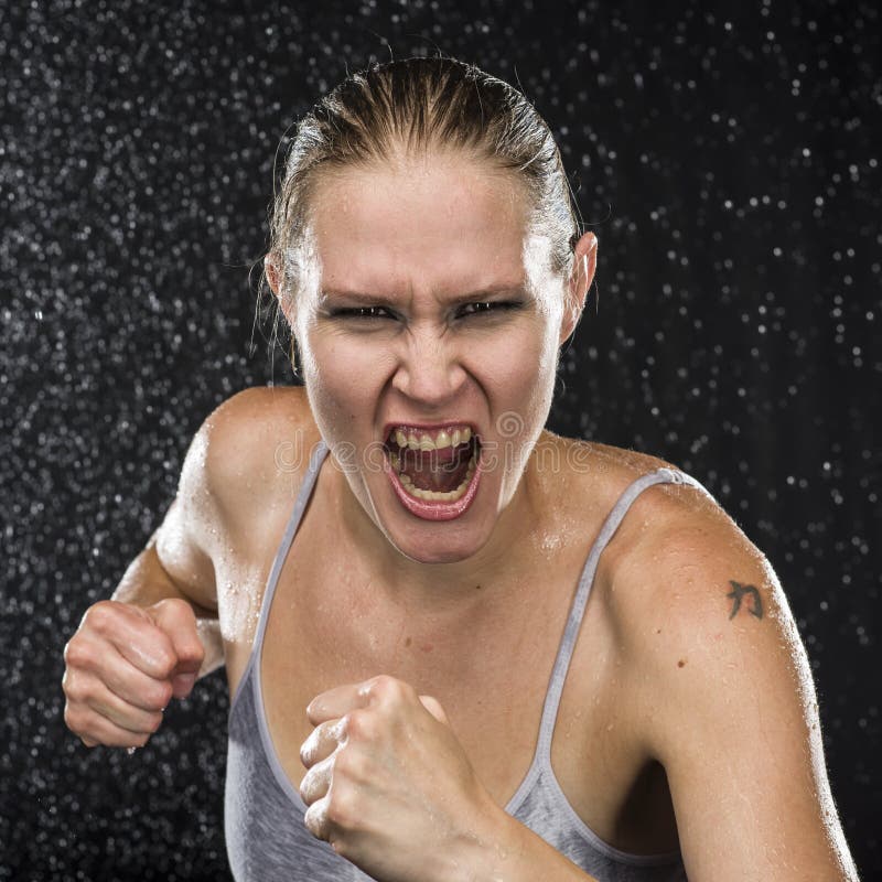 Close up Female Fighter in Combat Pose, Screaming at the Camera with Irate Facial Expression Against Water Drops Background. Close up Female Fighter in Combat Pose, Screaming at the Camera with Irate Facial Expression Against Water Drops Background.