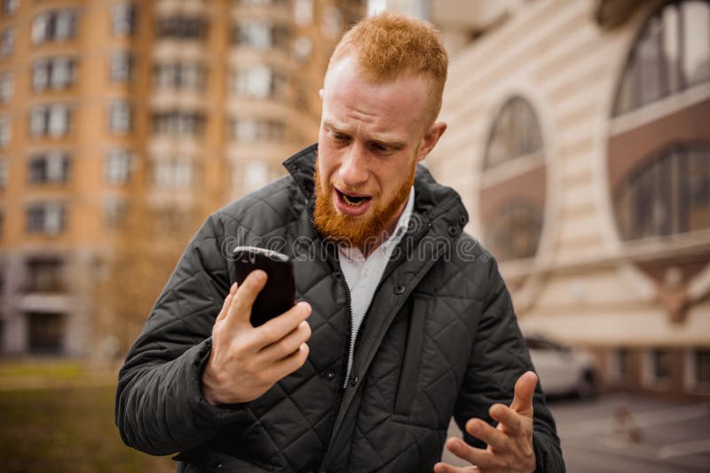 Angry ginger man screaming on phone outdoor. Angry ginger man screaming on phone outdoor