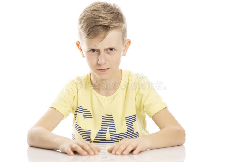 Ilsken tonårig grabb som sitter på tabellen Isolerat ?ver vitbakgrund arkivbild Ilsken tonårig grabb som sitter på tabellen Isolerat ?ver vitbakgrund arkivbild
