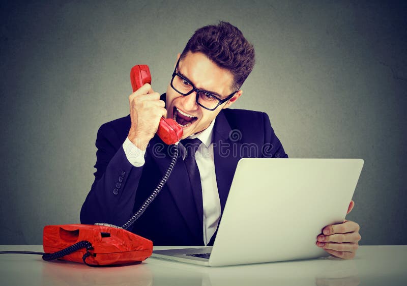 Angry business man calling customer service with a laptop failure screaming on the phone. Angry business man calling customer service with a laptop failure screaming on the phone