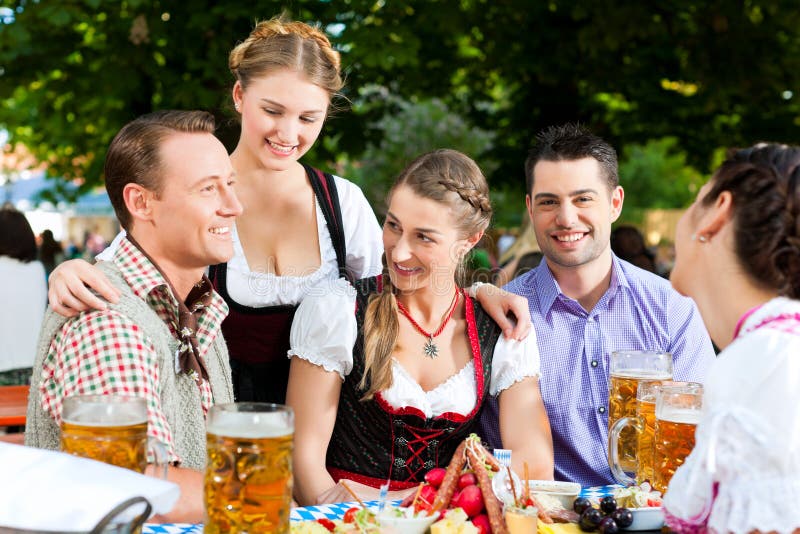 Im Biergarten - Freunde auf einer Tabelle mit Bier lizenzfreies stockbild Im Biergarten - Freunde auf einer Tabelle mit Bier lizenzfreies stockbild