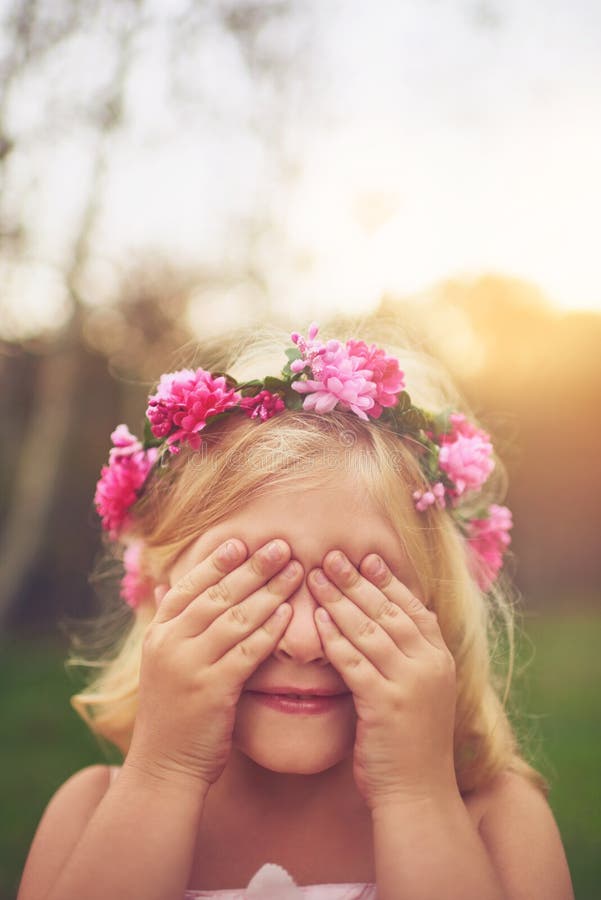 Im counting to ten, you better go hide. a cheerful little girl with her hands on her eyes playing hide and seek outside in nature