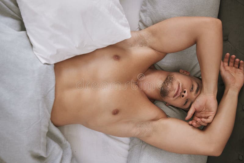 Im ready for the day. High angle portrait of a handsome and muscular young man lying in his bed at home.