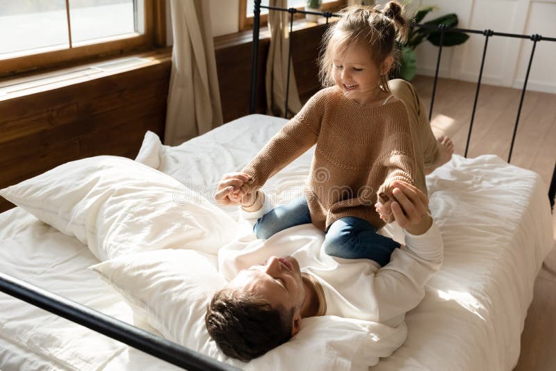 Im wenig Tochterspiel von morgen mit liebendem Vater im Bett stockbilder