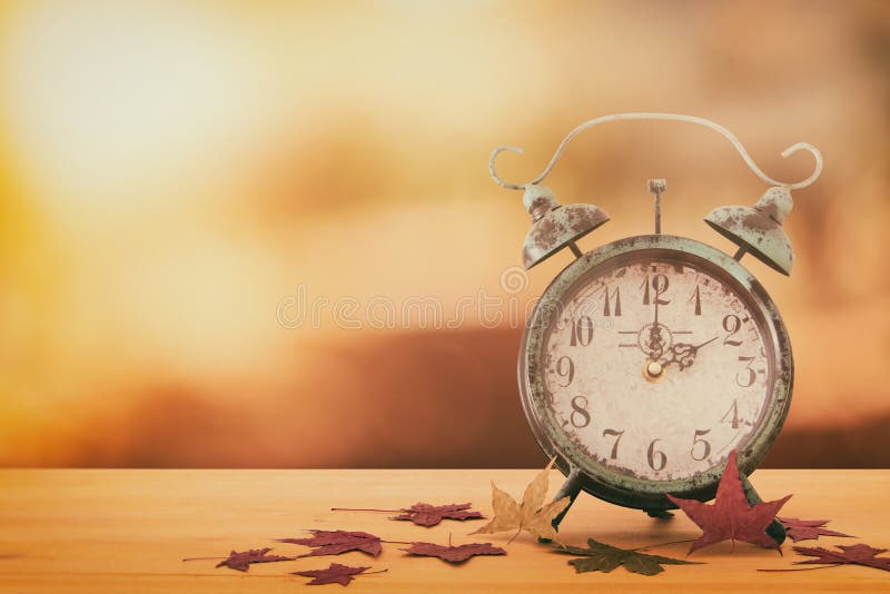 Image of autumn Time Change. Fall back concept. Dry leaves and vintage alarm Clock on rustic wooden table. royalty free stock photo Image of autumn Time Change. Fall back concept. Dry leaves and vintage alarm Clock on rustic wooden table. royalty free stock photo