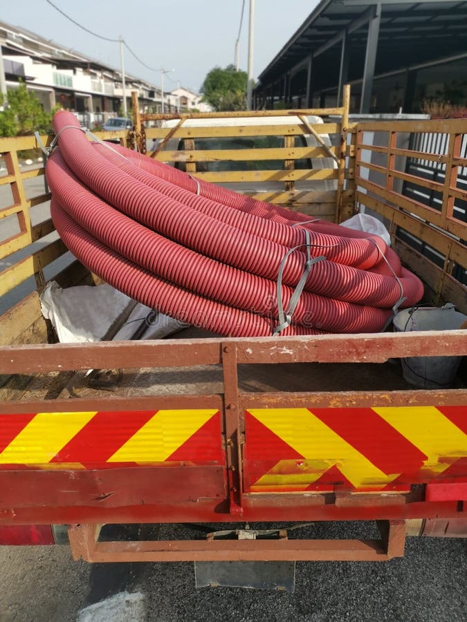 Bundle of Vermilion Red PVC Plastic Industrial Pipe Hose at the Back of