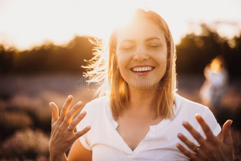 Charming caucasian mother smiling and gesturing against the sunshine with a lavender field on background royalty free stock photography Charming caucasian mother smiling and gesturing against the sunshine with a lavender field on background royalty free stock photography