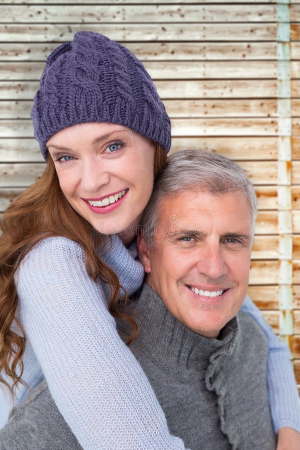 Happy couple in warm clothing against faded pine wooden planks. Happy couple in warm clothing against faded pine wooden planks