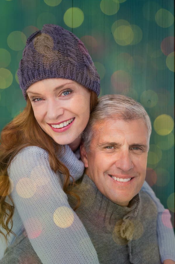 Happy couple in warm clothing against close up of christmas lights. Happy couple in warm clothing against close up of christmas lights