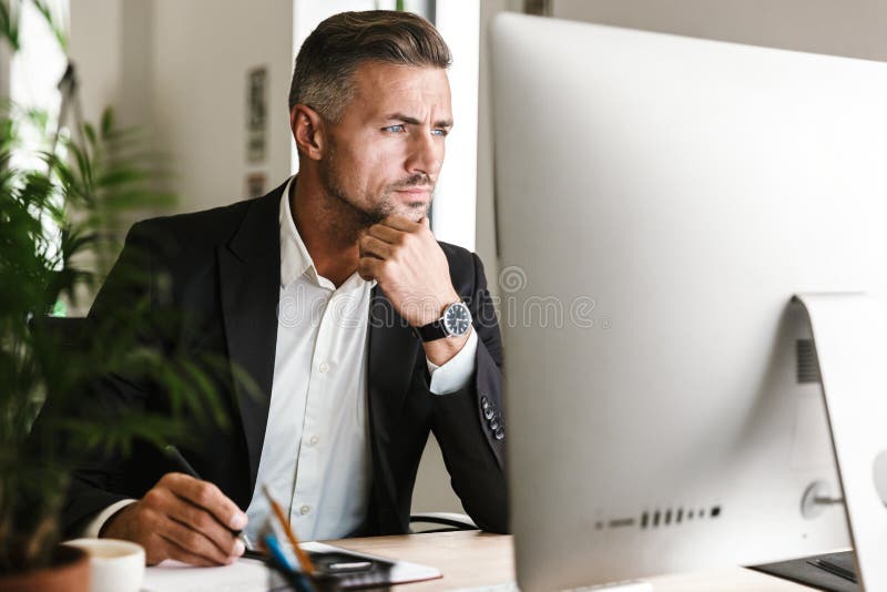 Image of confident businessman working in office and looking on computer stock images