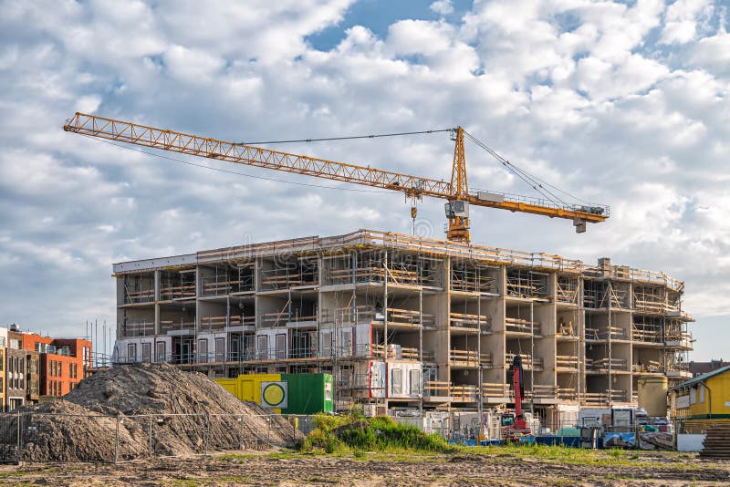 Construction of a house with a yellow tower crane on blue sky background