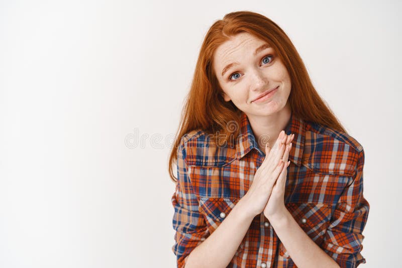Image of cute redhead woman asking for favour. Girl wtih ginger hair and blue eyes showng pleading sign and saying