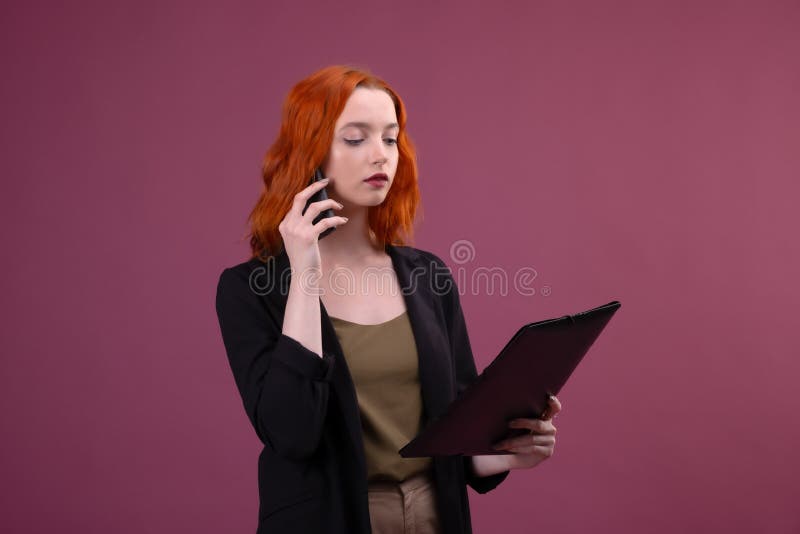 Image d'une belle femme rousse ?tonnante posant au-dessus du dossier rose de participation de fond parlant par le t?l?phone porta photographie stock libre de droits Image d'une belle femme rousse ?tonnante posant au-dessus du dossier rose de participation de fond parlant par le t?l?phone porta photographie stock libre de droits