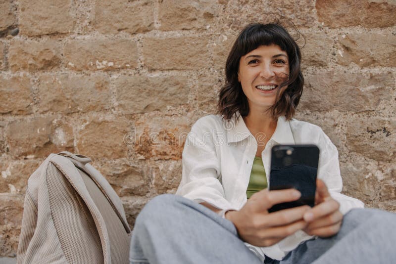 Image d'une européenne heureuse tenant un téléphone et regardant la caméra photographie stock libre de droits
