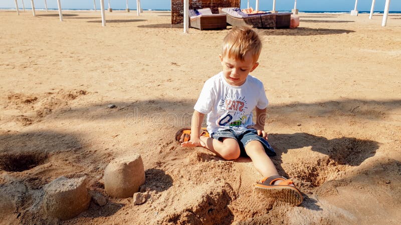 Image de 3 ann?es de petit gar?on d'enfant en bas ?ge s'asseyant sur la plage de mer et le ch?teau de construction du sable humid photos libres de droits Image de 3 ann?es de petit gar?on d'enfant en bas ?ge s'asseyant sur la plage de mer et le ch?teau de construction du sable humid photos libres de droits