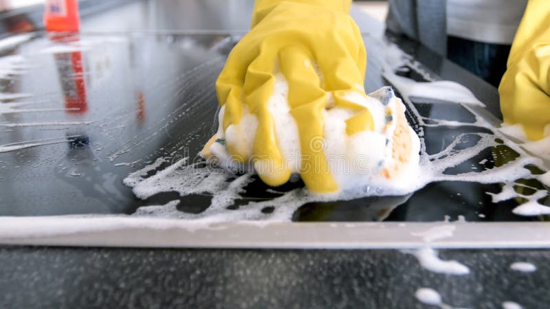 Image de plan rapproché de main dans le gant en caoutchouc jaune tenant l'éponge avec des lessives image libre de droits Image de plan rapproché de main dans le gant en caoutchouc jaune tenant l'éponge avec des lessives image libre de droits