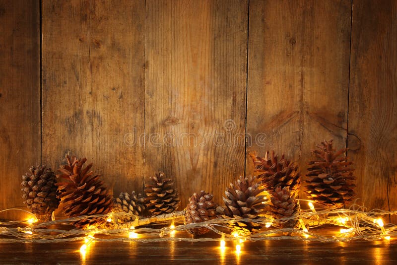 Image de vacances avec les lumières de guirlande de Noël et les cônes d'or de pin au-dessus du fond en bois image stock Image de vacances avec les lumières de guirlande de Noël et les cônes d'or de pin au-dessus du fond en bois image stock