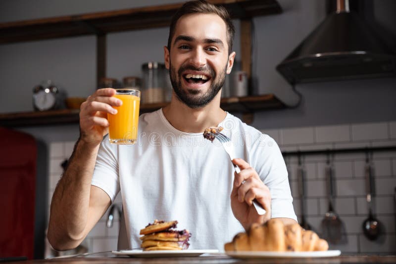 Image of european guy 30s eating food while having breakfast in modern apartment royalty free stock images Image of european guy 30s eating food while having breakfast in modern apartment royalty free stock images