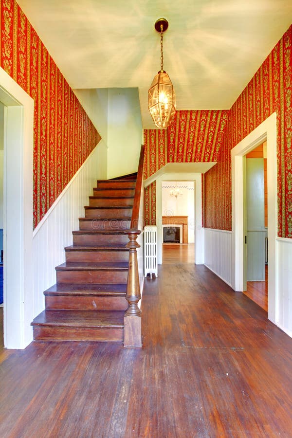 Image of Hallway with Wooden Staircase and Red Pattern Wallpaper Stock