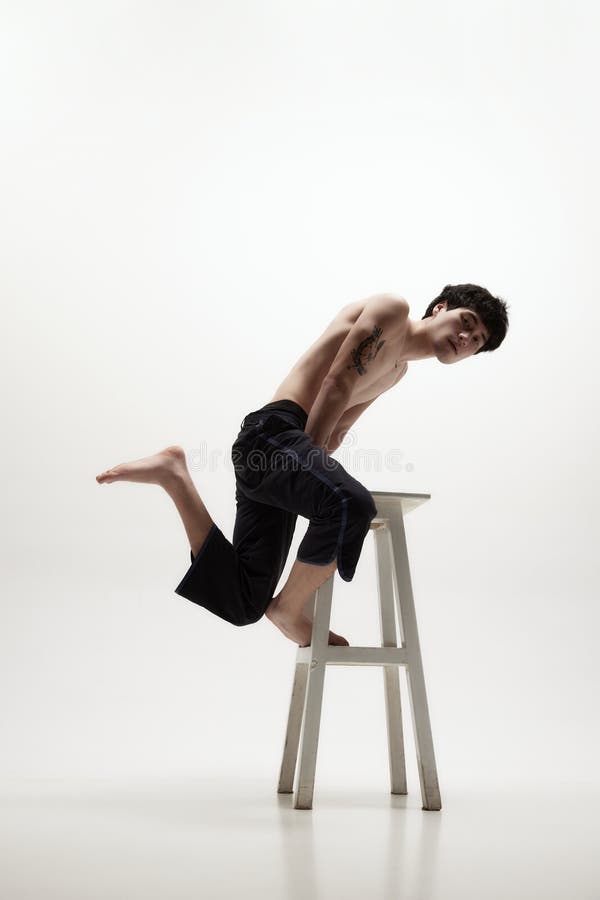 image handsome young man posing shirtless black trousers jumping high chair against white studio background concept male 274639944