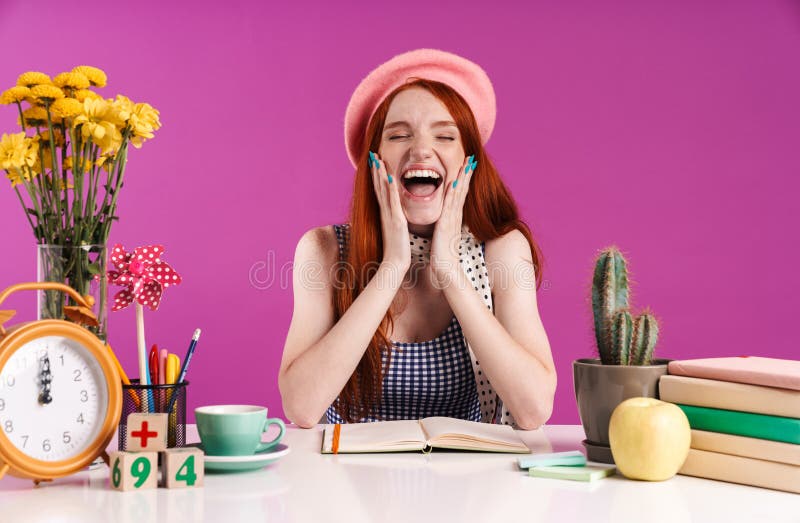 Image of happy teenage girl laughing while studying with books at desk