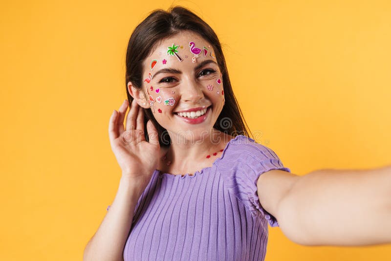 Image of happy woman with stickers on face smiling while taking selfie stock image