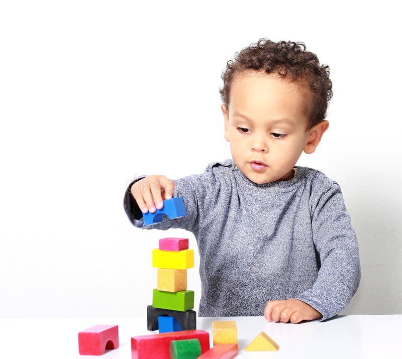 Image of little boy testing his creativity by building towers with toy building blocks and enjoying it tremendously