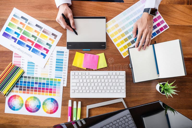 Image of male creative graphic designer working on color selection and drawing on graphics tablet at workplace with work tools and stock photo Image of male creative graphic designer working on color selection and drawing on graphics tablet at workplace with work tools and stock photo