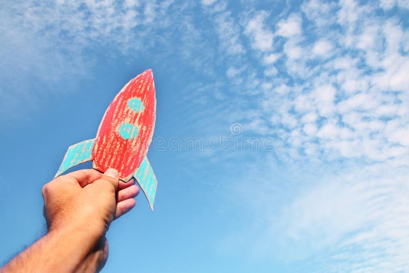 Image of male hand holding a rocket against the sky. imagination and success concept. royalty free stock images