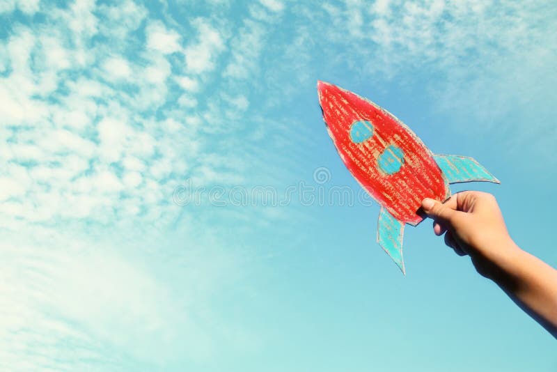 Image of male hand holding a rocket against the sky. imagination and success concept. stock photo