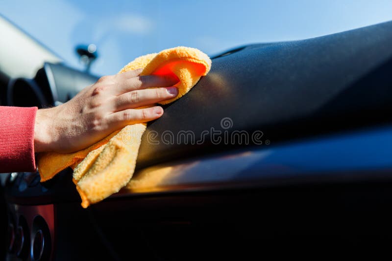 Image of man`s hand with orange rag washing car interior, close-up