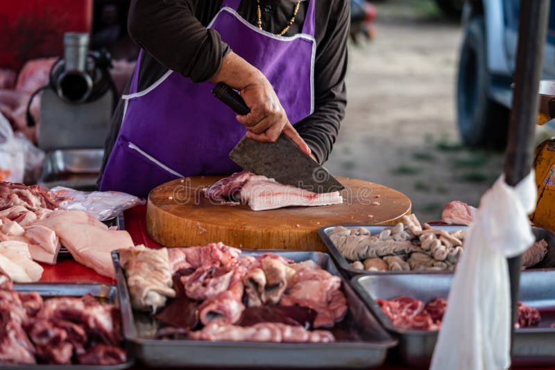 Image of a meat merchant Use a knife to cut pork on a wooden cutting board to sell at rural markets