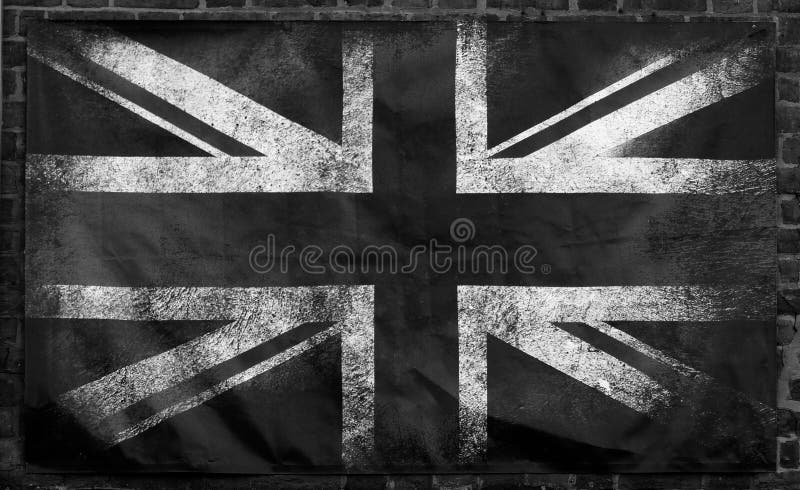 A monochrome image of an old stained dirty union jack british flag with dark crumpled edges on a brick wall background. A monochrome image of an old stained dirty union jack british flag with dark crumpled edges on a brick wall background