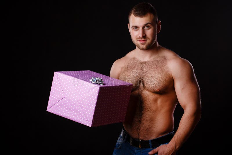 Image of muscular man holding xmas gifts, isolated on black