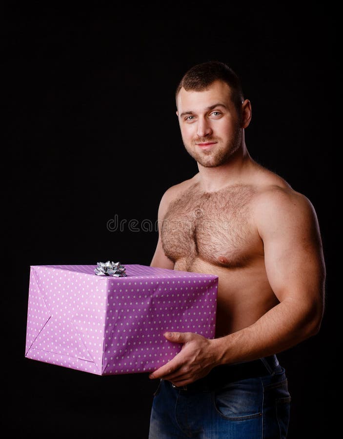 Image of muscular man holding xmas gifts, isolated on black