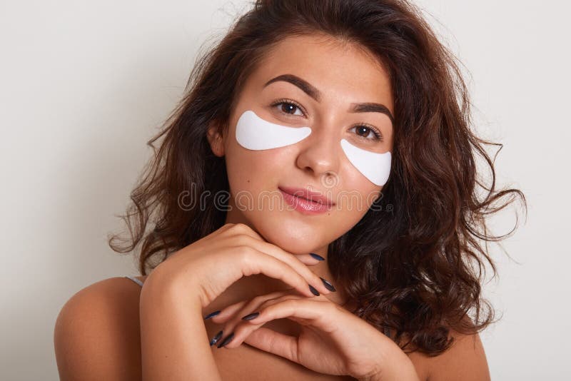 Image of peaceful charming young female standing isolated over white background in studio, putting hands close to face, having stock images Image of peaceful charming young female standing isolated over white background in studio, putting hands close to face, having stock images