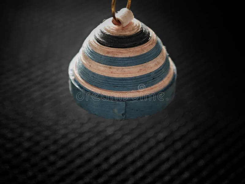 An image of a pendant made out of paper and strings. Paper and string pendant in close-up view