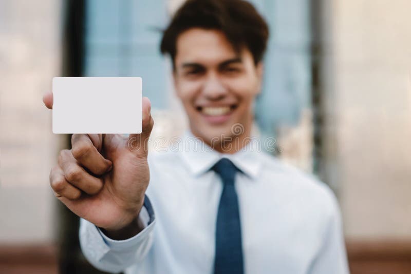 Image prototypes de cartes de visite. Jeune homme d'affaires heureux présenter une carte blanche de papier blanc photos stock