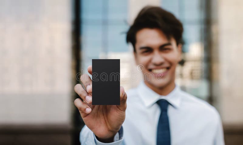 Image prototypes de cartes de visite. Le jeune homme d'affaires heureux présent une carte vierge noire est navigation encliquetage photos stock