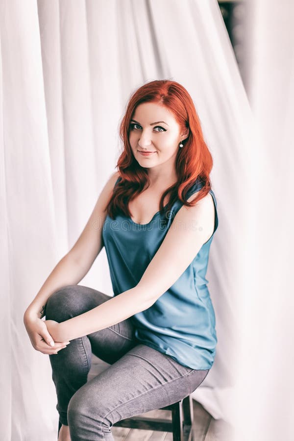 Image of redhead young happy lady in casual clothes sitting on chair on blurred white background looking camera royalty free stock photo Image of redhead young happy lady in casual clothes sitting on chair on blurred white background looking camera royalty free stock photo