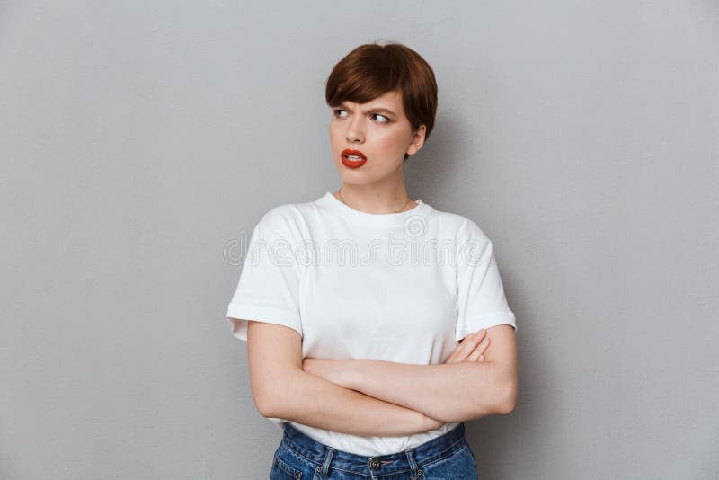 Image of resentful brunette woman frowning and standing with arms crossed