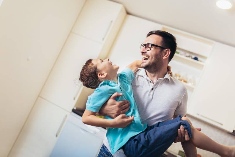 Satisfied smiling man piggybacking his son while having fun in modern studio apartment royalty free stock images Satisfied smiling man piggybacking his son while having fun in modern studio apartment royalty free stock images